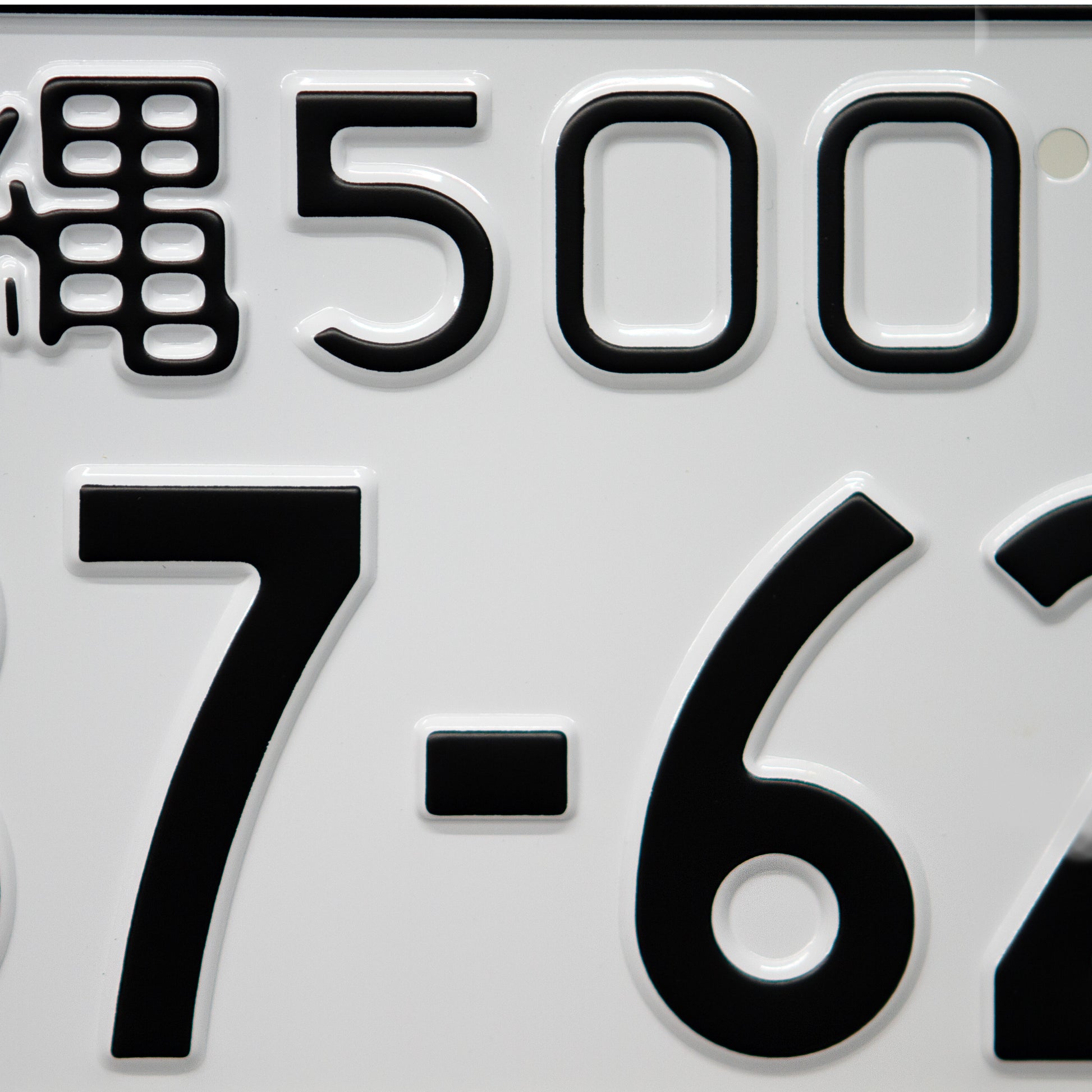 Japanese license plate gloss white with black text closeup